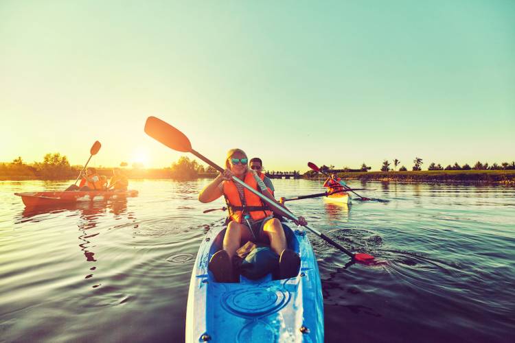 3 kayaks with 2 people per kayak floating at sunset