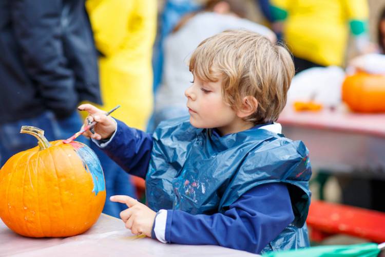 A little boy paints a pumpkin