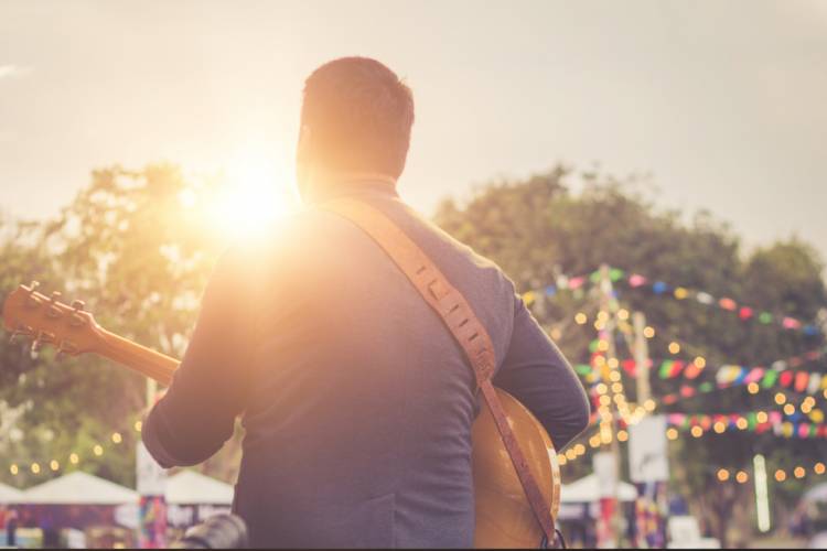 man with back to camera playing guitar on stage